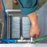 Image shows a mans hand reaching for a tap to turn on the water to the boot cleaner